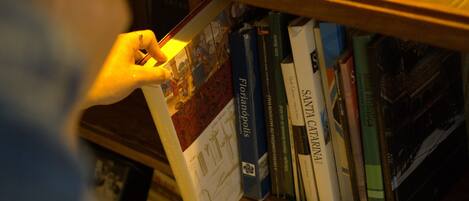 A bookshelf with books and a vase with red flowers.