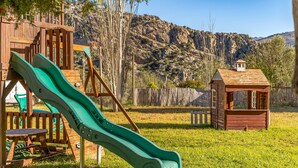 A playground with a green slide and a wooden playhouse. - 3 bedroom lovely home in Montejaque (Montejaque)