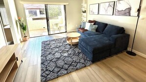 Un saló modern amb un sofà blau, una catifa amb dibuixos i un ventilador de sostre.