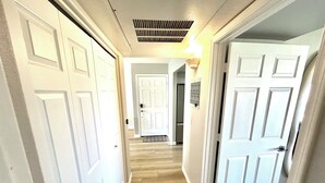 Un passadís amb portes blanques, un lluminari i una reixa al sostre.