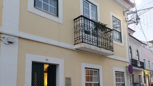 Um edifício de dois andares com varanda, uma porta com número e placa de proibido estacionar.