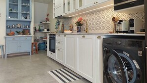 Cozinha com armários brancos, máquina de lavar e micro-ondas.