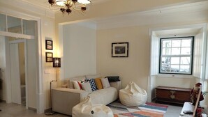 Uma sala de estar aconchegante com um sofá, cadeiras de poltrona, um tapete estampado e uma janela com vista.