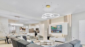 Una sala de estar moderna con un sofá, sillones, una mesa de centro y un televisor montado en la pared.