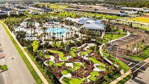Vista aérea de un resort con piscina, jardines ajardinados y zona de estacionamiento.