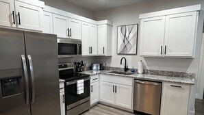Una cocina moderna con armarios blancos, electrodomésticos de acero inoxidable y encimera de granito.