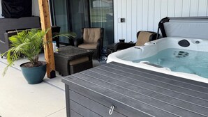 Un jacuzzi con terraza de madera, una silla y una planta en maceta.