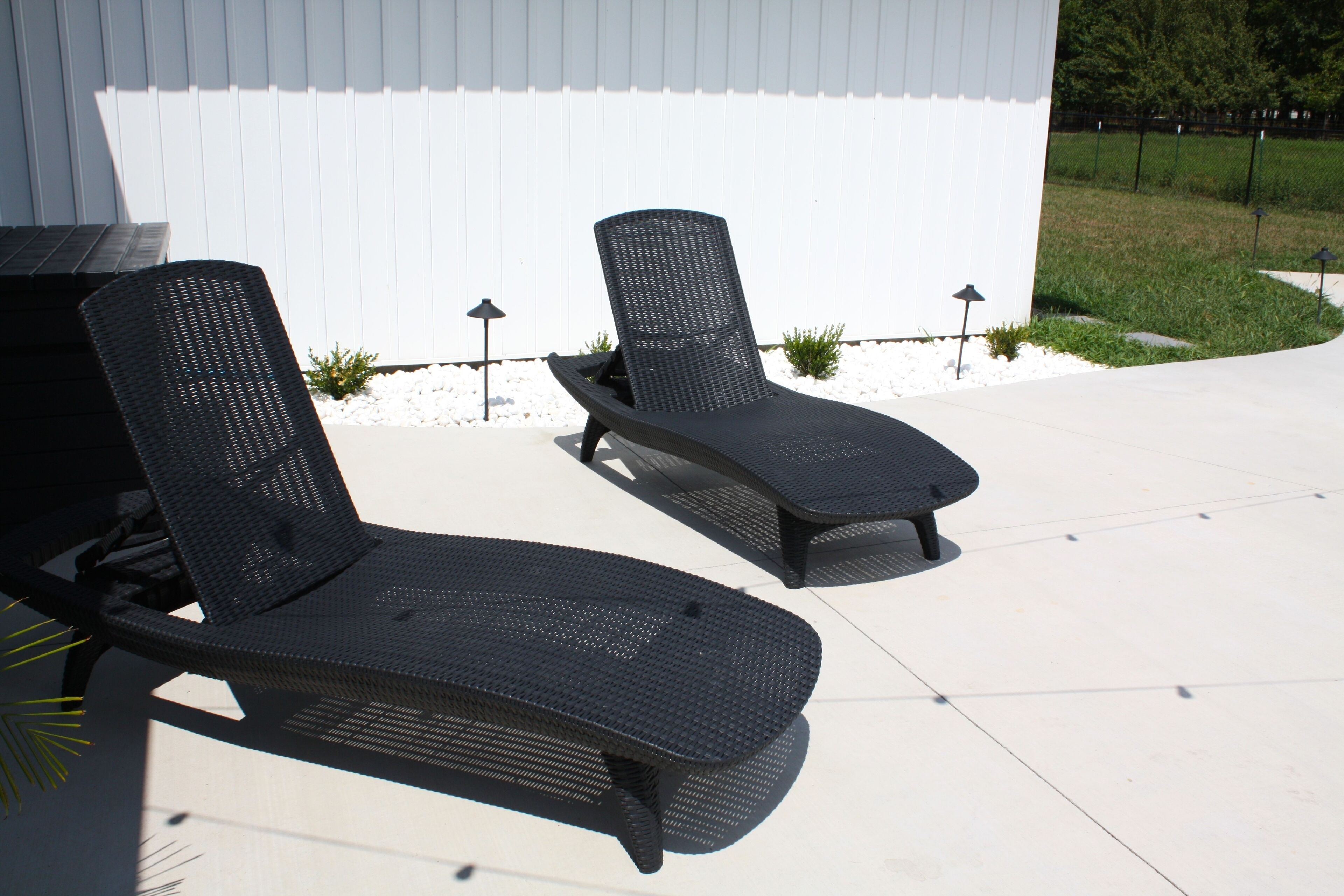 Two outdoor lounge chairs with a white building in the background.