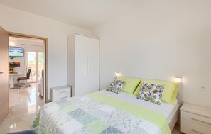 A bedroom with a bed, bedside tables, a TV, and a sliding door leading to a balcony.