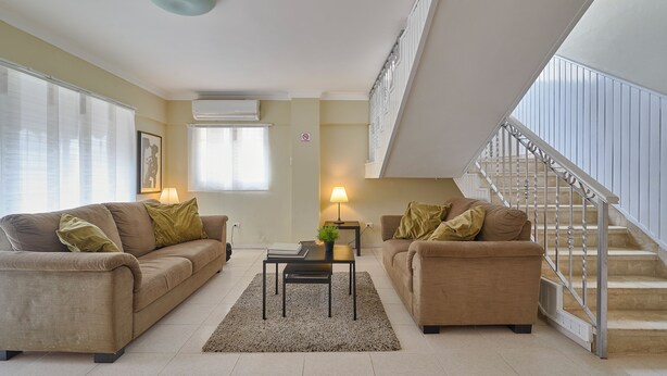 A modern living room with two sofas, a coffee table, and a staircase. -  Penthouse in Evaristo Morales Sleeps 14 (Santo Domingo)