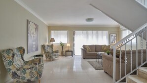 A spacious living room with a sofa, armchair, and a staircase. -  Penthouse in Evaristo Morales Sleeps 14 (Santo Domingo)