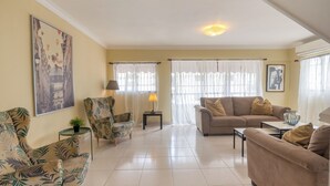 A living room with a sofa, armchairs, a coffee table, and a lamp. -  Penthouse in Evaristo Morales Sleeps 14 (Santo Domingo)