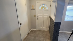 A hallway with a white door, a stained glass window, and a stone accent wall.