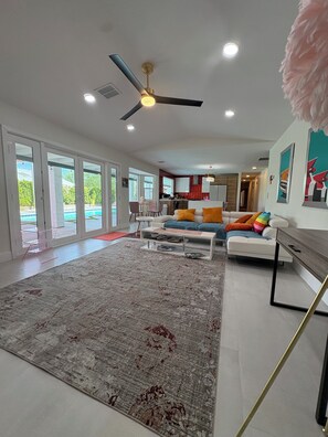 Un salon moderne avec un grand tapis, un ensemble de canapés, une table basse et un ventilateur de plafond.