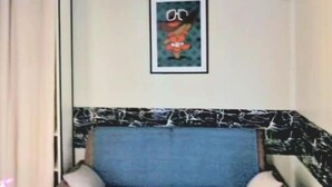 Una habitación con un sofá azul, un cuadro en la pared y un cabecero estampado en blanco y negro.
