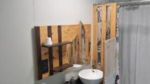 Un baño con un estante de madera, un lavabo blanco y una cortina de ducha.