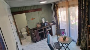 Un espacio habitable compacto con área de cocina, una mesa de comedor con sillas y una pequeña zona de estar con mesa y sillas.