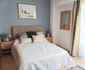 A bedroom with a bed, nightstands, a mirror, and a painting on the wall. - **************************************************** (Grau i Platja)