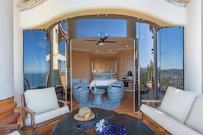 A balcony with a bed, two chairs, a table with drinks, and a city view. - Escape to Casa Ensueño, a stunning three-story luxury villa with ocean views. (Sayulita)