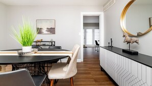 Un espace repas moderne avec une table noire, des chaises blanches et une plante en pot.