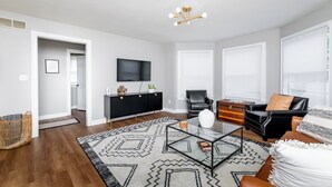 Un salon moderne avec un canapé en cuir noir, une table basse en verre et un meuble de rangement noir pour appareils multimédias.