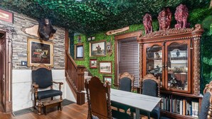 A room with a wooden staircase, a dining table with chairs, a large wooden cabinet with glass doors, and a wall decorated with framed pictures and a bear head. - ★★ The Red Lion ★★. OSU British Pubcade Castle (Columbus)