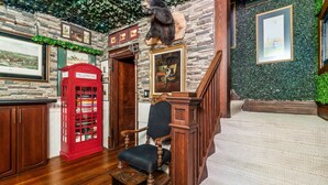 A room with a wooden staircase, a red telephone booth, and a bear statue. - ★★ The Red Lion ★★. OSU British Pubcade Castle (Columbus)