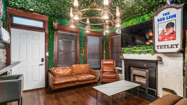 A cozy living room with a leather sofa, a chair, a small table, and a fireplace. There is a sign on the wall that reads "The Red Lion TETLEY". - ★★ The Red Lion ★★. OSU British Pubcade Castle (Columbus)