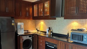 Eine moderne Küche mit Holzausstattung, einem Edelstahlkühlschrank, einer integrierten Waschmaschine, einem Geschirrspüler und einer Mikrowelle.
