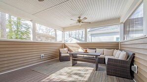Ein überdachter Patio-Bereich mit Deckenventilator, einer Sofagruppe und einem Tisch.