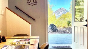 A room with a wooden table, a chair, a door leading outside, and a wall with a lotus symbol. - Mount Shasta is calling - Amazing Views- The House of Light - Pet Friendly (Mount Shasta)