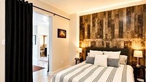 A hotel room with a bed, a wooden accent wall, a door, and a hallway leading to another room. - Mount Shasta is calling - Amazing Views- The House of Light - Pet Friendly (Mount Shasta)