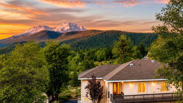A two-story house with a balcony, surrounded by trees and a mountain in the background. - Mount Shasta is calling - Amazing Views- The House of Light - Pet Friendly (Mount Shasta)