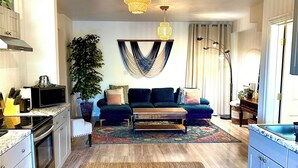 A modern kitchen with a microwave, stove, and cabinets. There is a dining area with a sofa and a rug. A large plant is in the corner. - Mount Shasta is calling - Amazing Views- The House of Light - Pet Friendly (Mount Shasta)