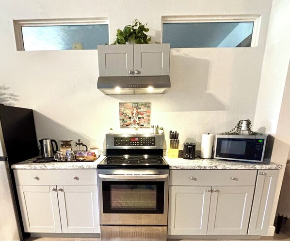 Una cocina equipada con estufa, horno, microondas y armarios.