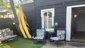 A patio with two patterned chairs, a small table, and a potted plant.