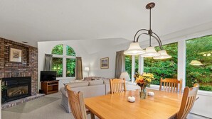 Un comedor con una mesa y sillas de madera, una chimenea, un sofá y un televisor.