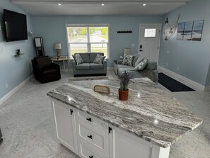 A modern kitchen with a marble countertop, white cabinets, and a small island.