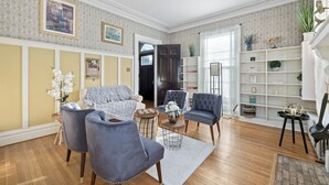 Ein Wohnzimmer mit einer Couch, zwei Sesseln, einem Couchtisch und einem Bücherregal.