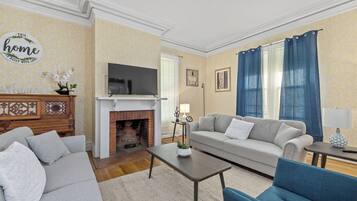 Een woonkamer met een open haard, bank en televisie.
