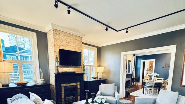 A modern living room with a fireplace, a television, and a dining area in the background.