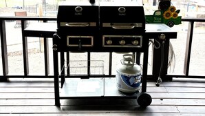 A covered outdoor area with a barbecue grill, a propane tank, and a table with chairs. - Cielo’s Retreat, A Charming 3-bedroom farmhouse in McKinneyprincenton (McKinney)
