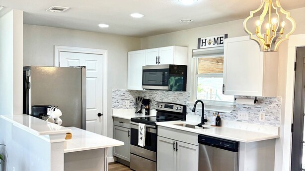 A modern kitchen with white cabinetry, stainless steel appliances, and a wooden floor. - Cielo’s Retreat, A Charming 3-bedroom farmhouse in McKinneyprincenton (McKinney)