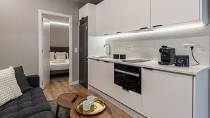 A compact kitchen with a built-in dishwasher, a coffee maker, and a microwave. - Waou Essence IV Antón Martín - Corta Duración (Madrid)