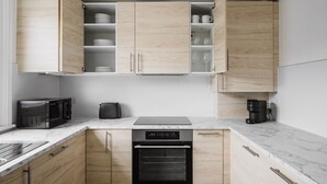 A modern kitchen with light wood cabinets, a built-in oven, a microwave, a toaster, and a coffee maker. - Blueground | Notting Hill, w/d, nr Hyde Park (London)