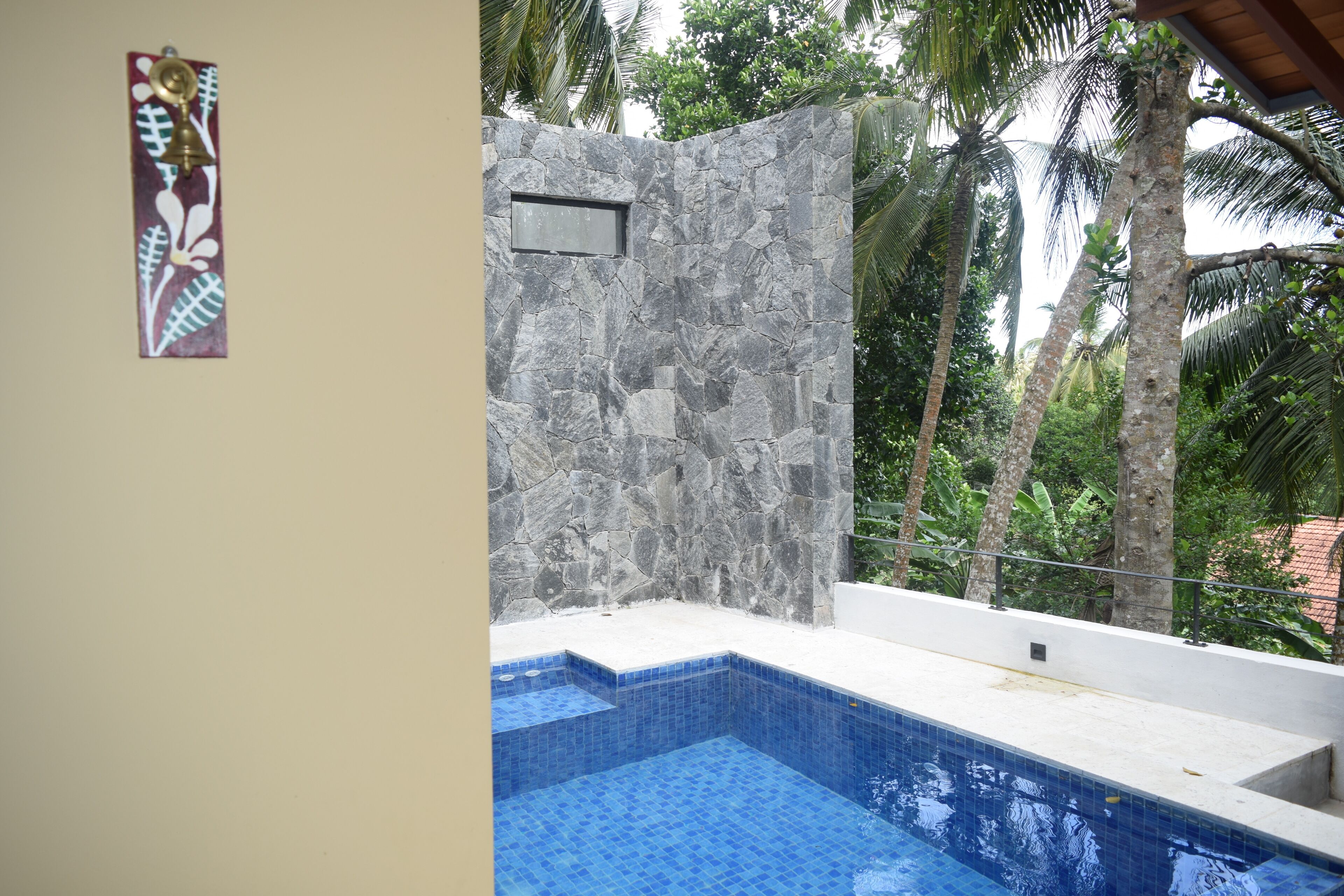 A swimming pool with blue tiles, a stone wall, and a small window.