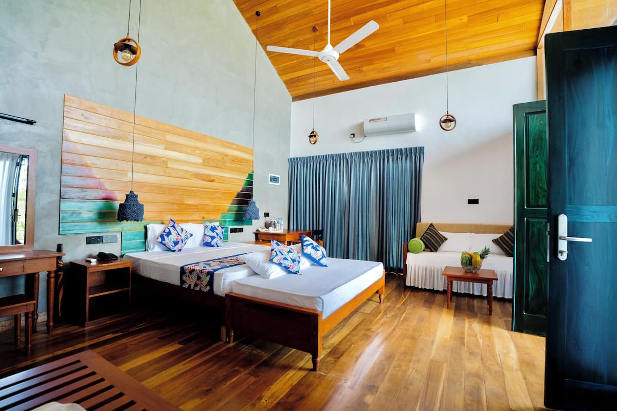 A spacious bedroom with a large bed, wooden ceiling, and a desk with a chair.