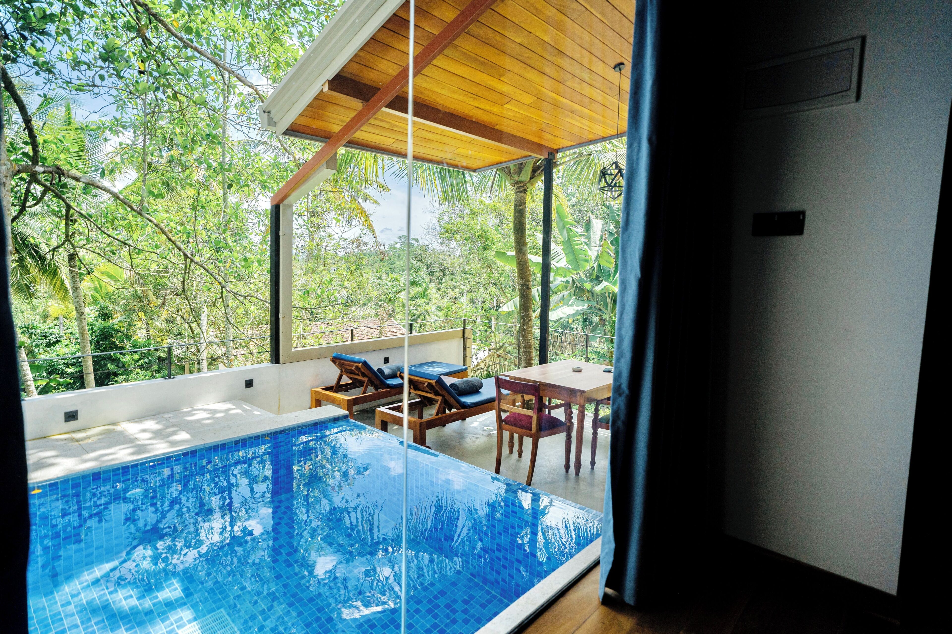 A modern pool area with a glass enclosure, wooden deck, and lounge chairs.