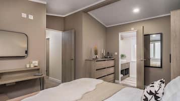 A bedroom with a bed, a dresser, a mirror, and a door leading to a bathroom.
