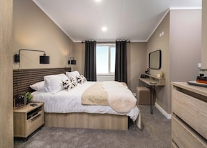 A modern bedroom with a bed, bedside tables, a desk, and a mirror. - Premium modern and contemporary luxury lodge perfect for a relaxing escape. (Workington)